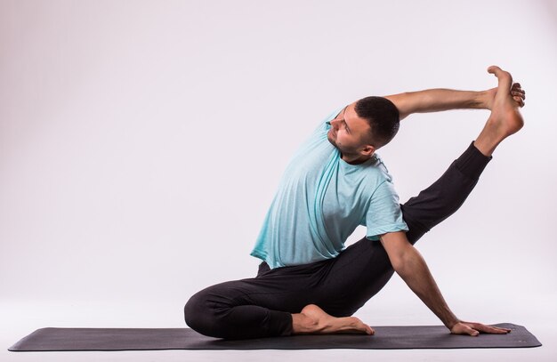 Concetto di yoga. Uomo bello che fa esercizio di yoga isolato su sfondo bianco