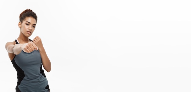 Concetto sano e fitness Ritratto di donna afroamericana che perfora in aria con la faccia sicura isolata su sfondo bianco