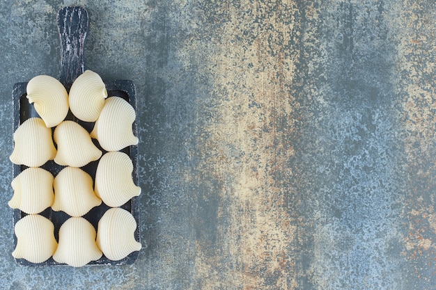 Condire le paste nel vassoio, sulla superficie di marmo.