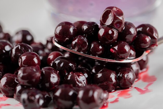 Confettura di ribes nero rosso nel piattino e in un cucchiaio metallico.