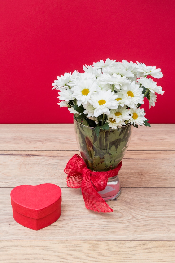 Foto gratuito confezione regalo a forma di cuore con bouquet di margherite in vaso