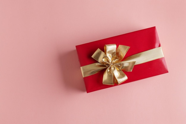 Confezione regalo con nastro dorato su sfondo rosa