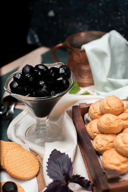 Confiture tradizionale nero della noce in un barattolo di vetro con i biscotti di burro su un bordo di legno