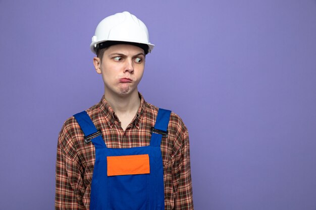 Confuso cercando lato giovane costruttore maschio che indossa l'uniforme