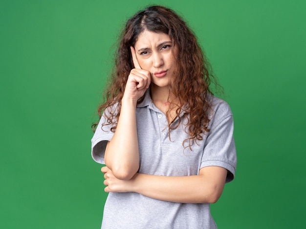 Confuso giovane bella ragazza caucasica guardando a lato facendo pensare gesto isolato sulla parete verde con copia spazio