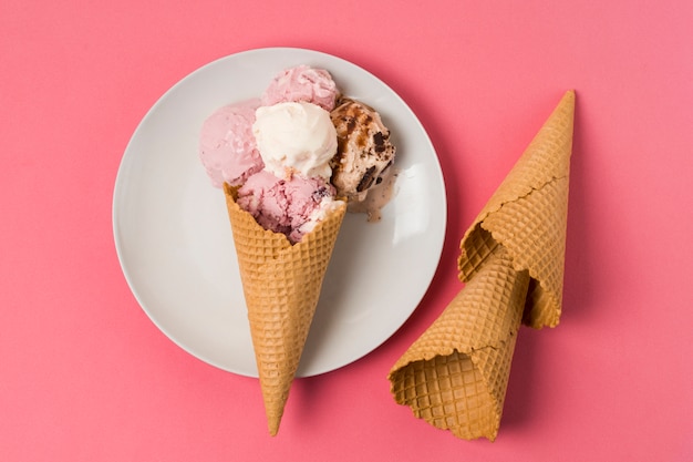 Coni di cialda con gelato su piatto e coni vuoti