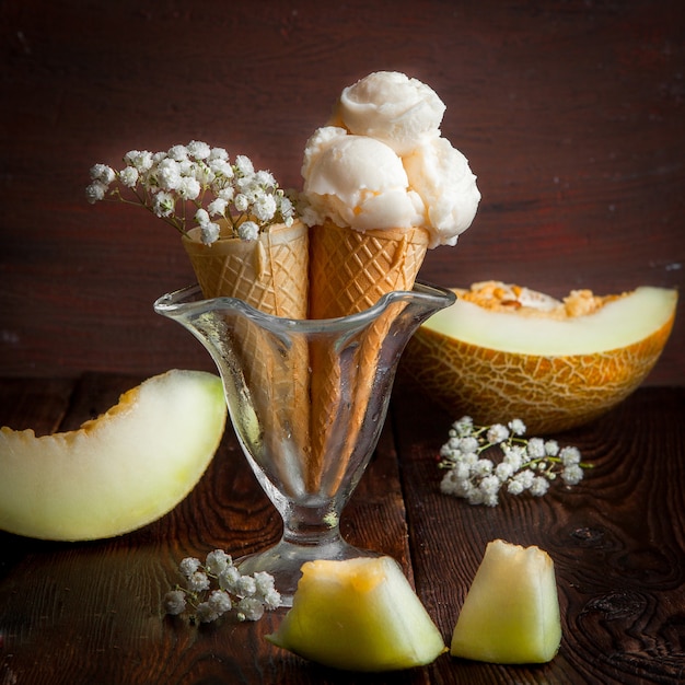 Coni di cialda vista laterale con fette di melone e gelato e gypsophila in coppa di gelato