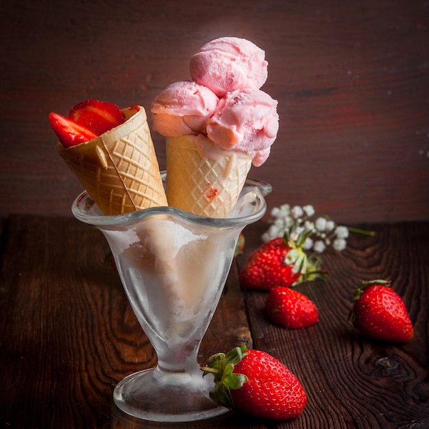 Coni di cialda vista laterale con fragola e gelato e gypsophila in coppa gelato