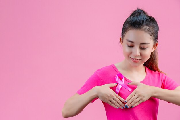 Consapevolezza del cancro al seno, donna in maglietta rosa con nastro di raso rosa sul petto, a sostegno della consapevolezza del cancro al seno simbolo