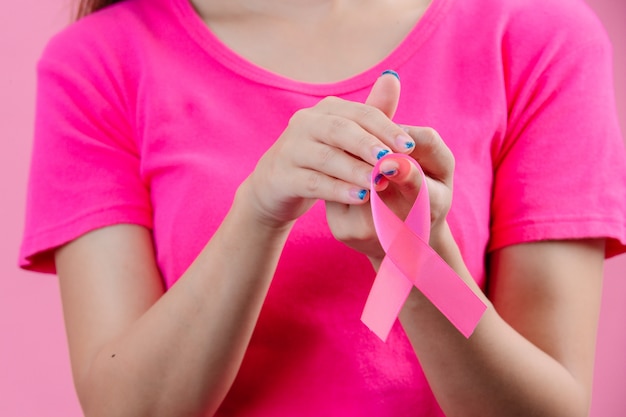 Consapevolezza del cancro al seno, un nastro rosa sulla mano di una donna è un simbolo per la Giornata mondiale del cancro al seno.