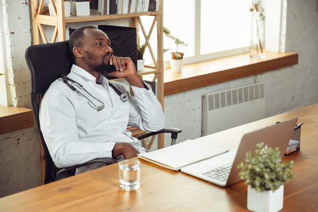 Consulenza medica per paziente, calma e allegra. Medico afroamericano durante il suo lavoro con i pazienti, spiegando le ricette per la droga. Duro lavoro quotidiano per la salute e il salvataggio di vite durante l'epidemia.