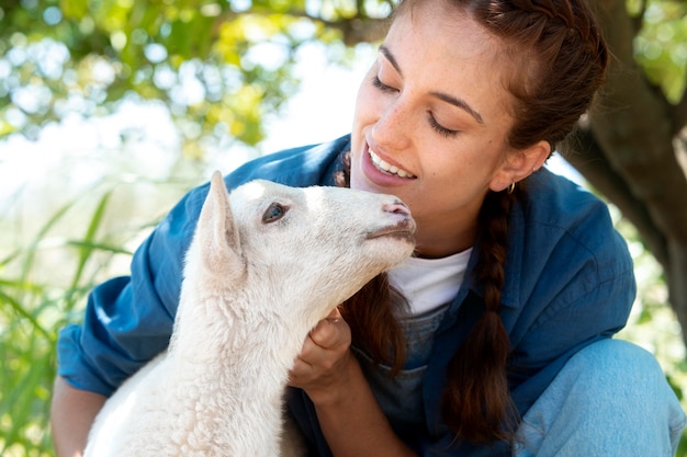 Contadina che tiene in braccio un cucciolo di pecora