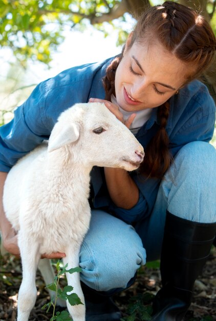 Contadina che tiene in braccio un cucciolo di pecora