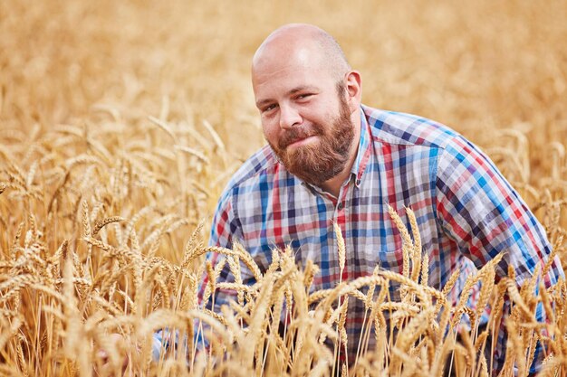 Contadino che cammina attraverso un campo di grano