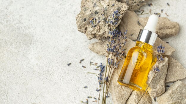 Contagocce dell'olio e lavanda sulle rocce con lo spazio della copia