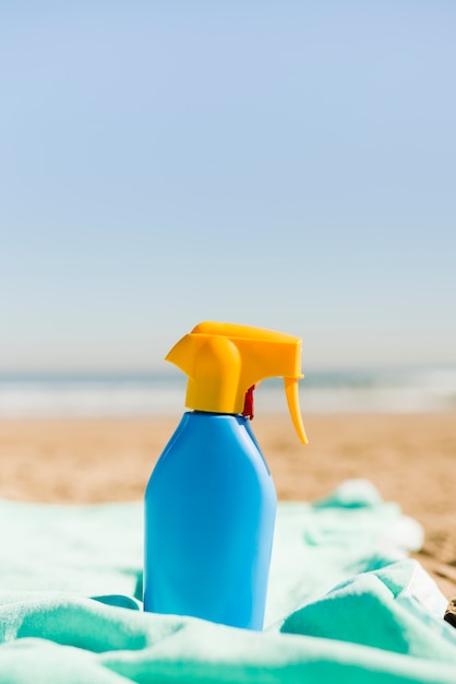 Contenitore blu chiuso dei cosmetici della protezione solare sulla coperta del turchese alla spiaggia