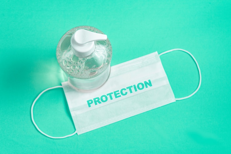 Foto gratuito contenitore con gel alcolico e maschera chirurgica sull'azzurro