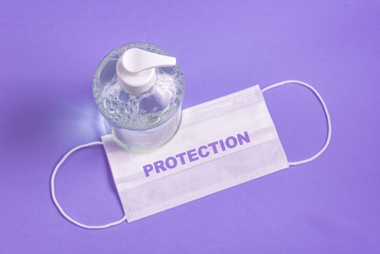 Foto gratuito contenitore con gel alcolico e maschera chirurgica sull'azzurro