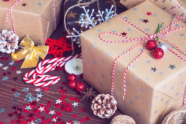 Contenitore di regalo della festa di Natale sulla tavola festiva decorata con le noci dei bastoncini di zucchero filato delle pigne e le stelle della scintilla su fondo di legno