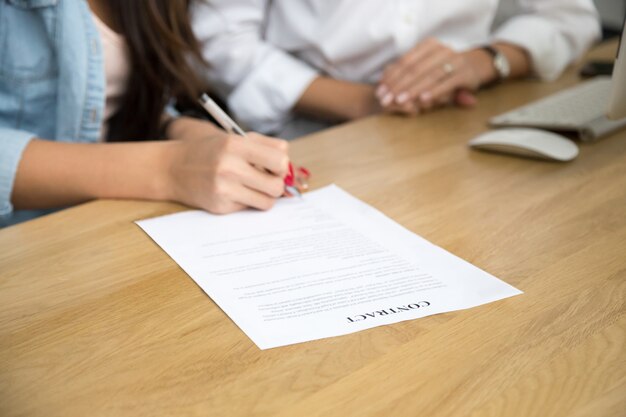 Contratto di firma della donna, mano femminile che mette firma scritta sul documento