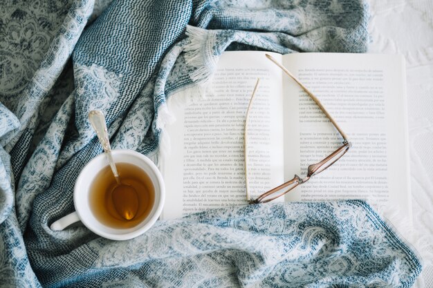 Coperta vicino a tè e libro aperto