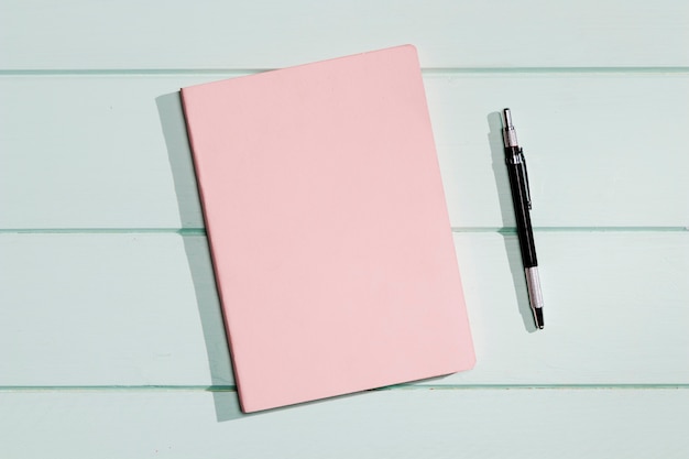 Copertina rosa di un blocco note con penna