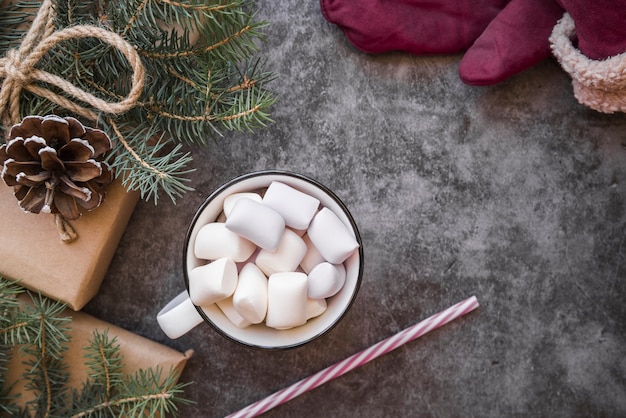 Coppa con marshmallow vicino tubo di plastica, ramoscelli di abete e scatole presenti