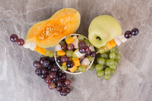Coppa di frutta e frutta fresca sulla superficie in marmo.