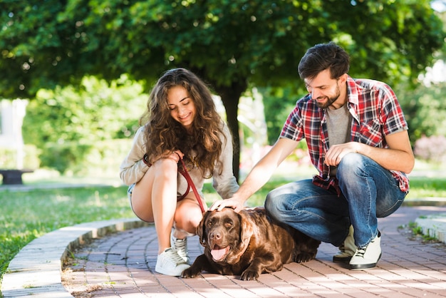 Coppia accarezzando il loro cane nel parco