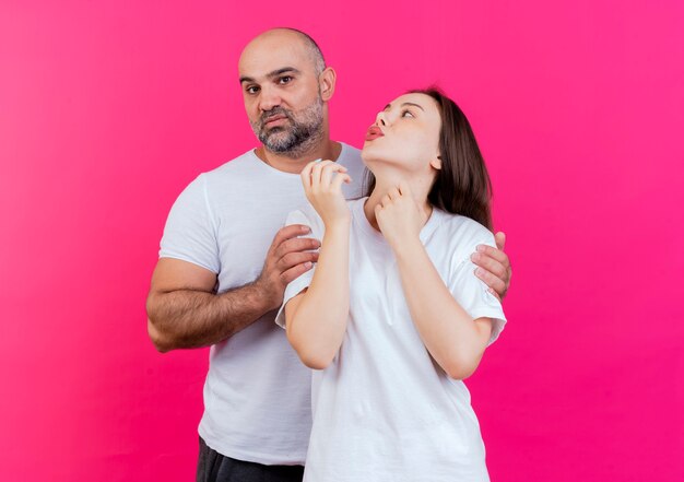 Coppia adulta uomo rigoroso tenendo la donna dalle spalle e guardando e lei lo guarda e fa il gesto di bacio