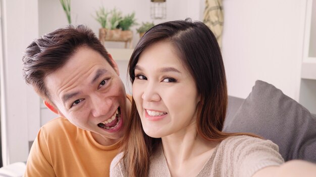 Coppia asiatica usando smartphone VIDEO Chiama con un amico in salotto a casa