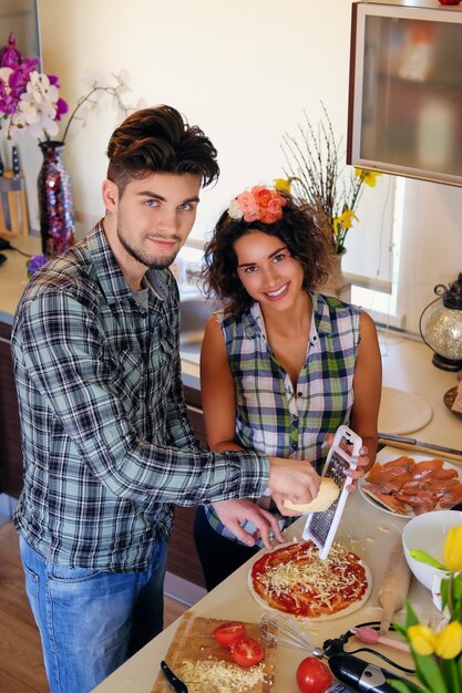 Coppia attraente di bruna femmina e un maschio in camicia di pile che cucinano il cibo in una cucina di famiglia.