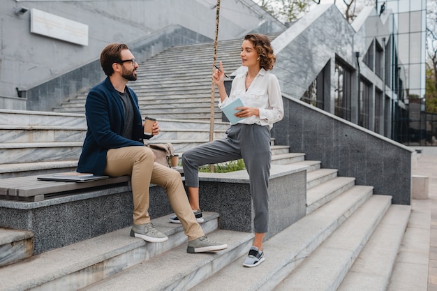 Coppia attraente di uomo e donna seduti sulle scale in città urbana