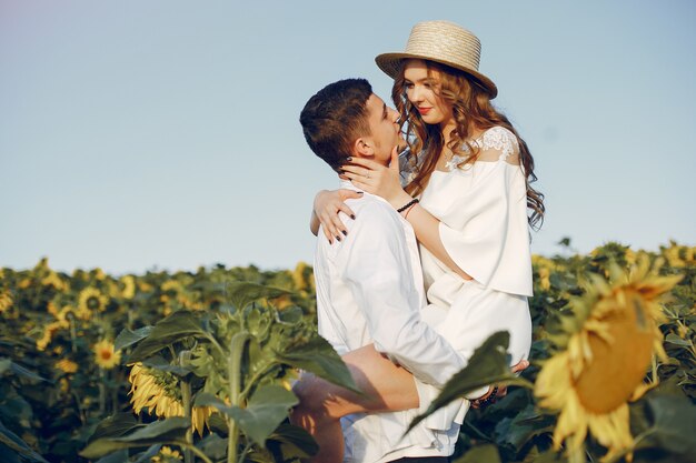 Coppia bella ed elegante in un campo con girasoli