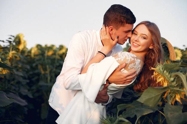 Coppia bella ed elegante in un campo con girasoli