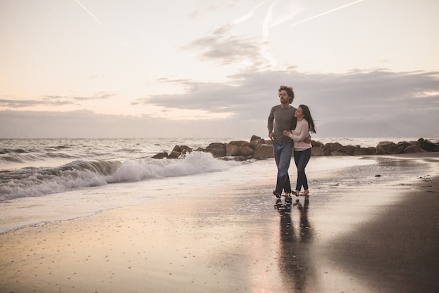 Coppia camminare sulla spiaggia al tramonto