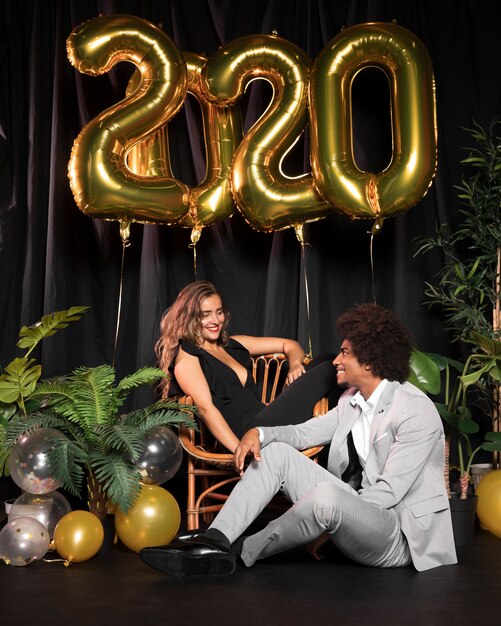 Coppia carina guardando l'altro circondato da palloncini con 2020 nuovo anno