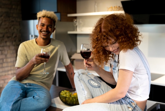 Coppia che beve vino insieme nella cucina della loro nuova casa