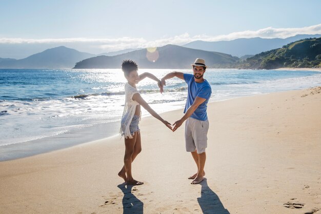 Coppia che formano cuore alla spiaggia