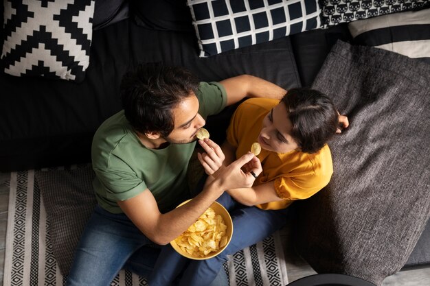 Coppia che mangia insieme a casa sul divano