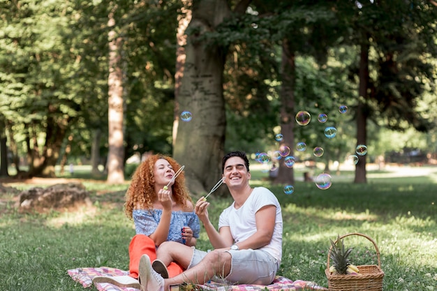 Coppia che soffia bolle al parco