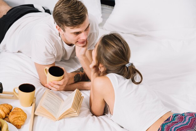 Coppia con caffè sdraiato sul letto