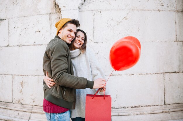 Coppia con palloncino e sacco di carta che abbraccia