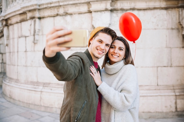 Coppia con palloncino prendendo selfie