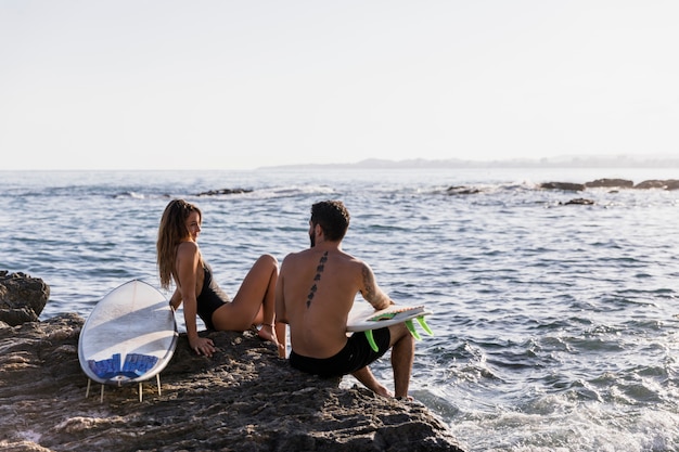 Coppia con tavole da surf a guardare l&#39;un l&#39;altro in riva al mare