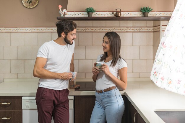 Coppia con tazze in cucina al mattino