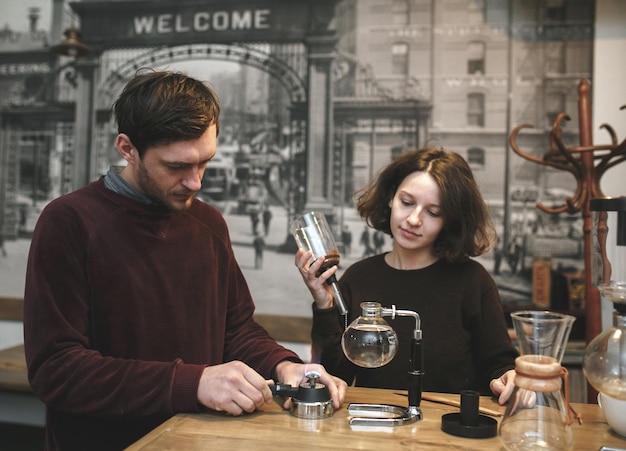 Coppia d'epoca che prepara il caffè con la caffettiera sottovuoto. Caffetteria. Tonalità vintage