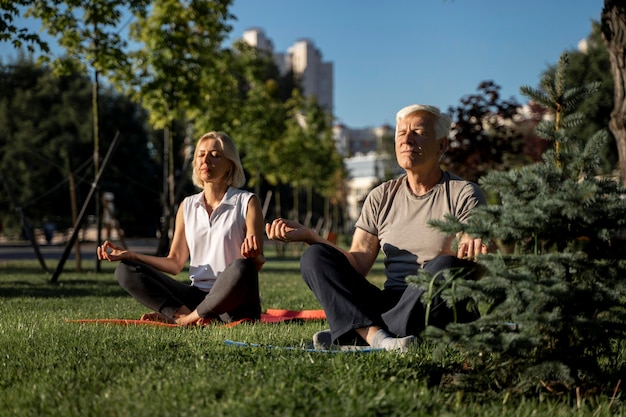 Coppia di anziani a praticare yoga all'esterno