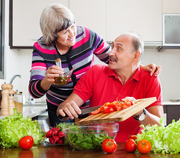 coppia di anziani che cucina con pomodori