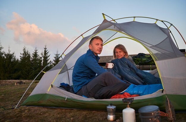 Coppia di campeggiatori che si rilassano in tenda all'aperto